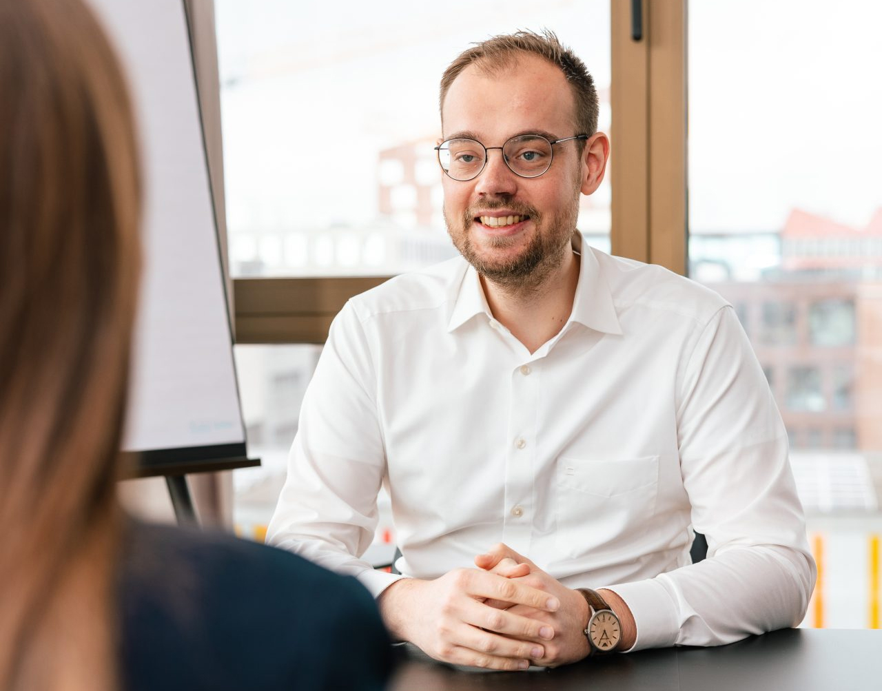 Die OPATZ Management GmbH kümmert sich um übergeordnete Aufgaben. Ein Mitarbeiter lächelt in einer Gesprächssituation.